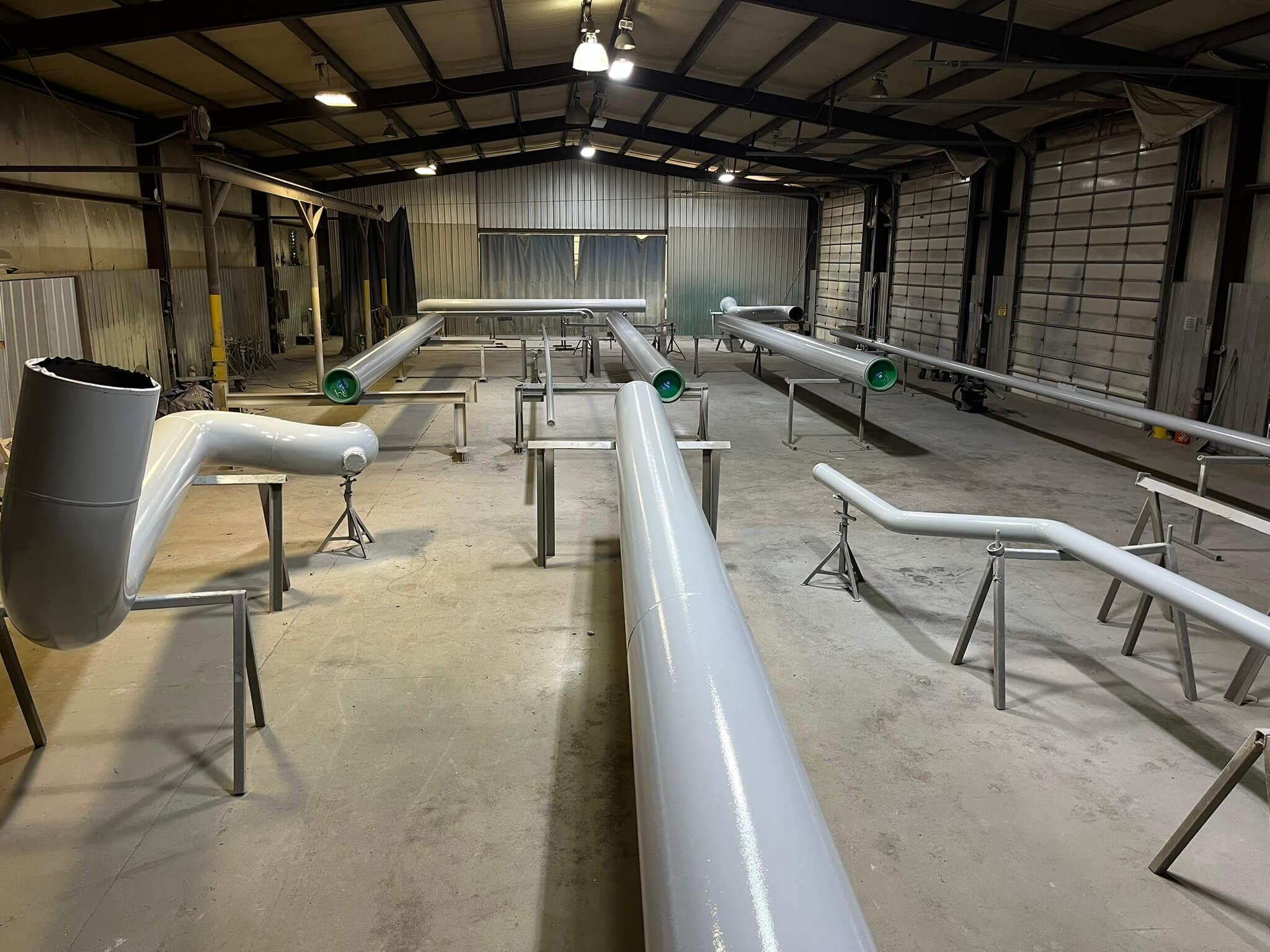 Large industrial pipes set up in a workshop, prepared for assembly with various angles and sizes displayed